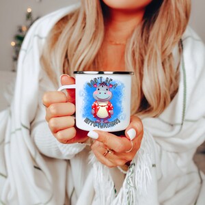 May include: White enamel mug with a blue and white watercolor background. The mug features a cartoon hippopotamus wearing a red and white Hawaiian shirt. The text "Don't be a Hippo-potamus" is printed on the mug.