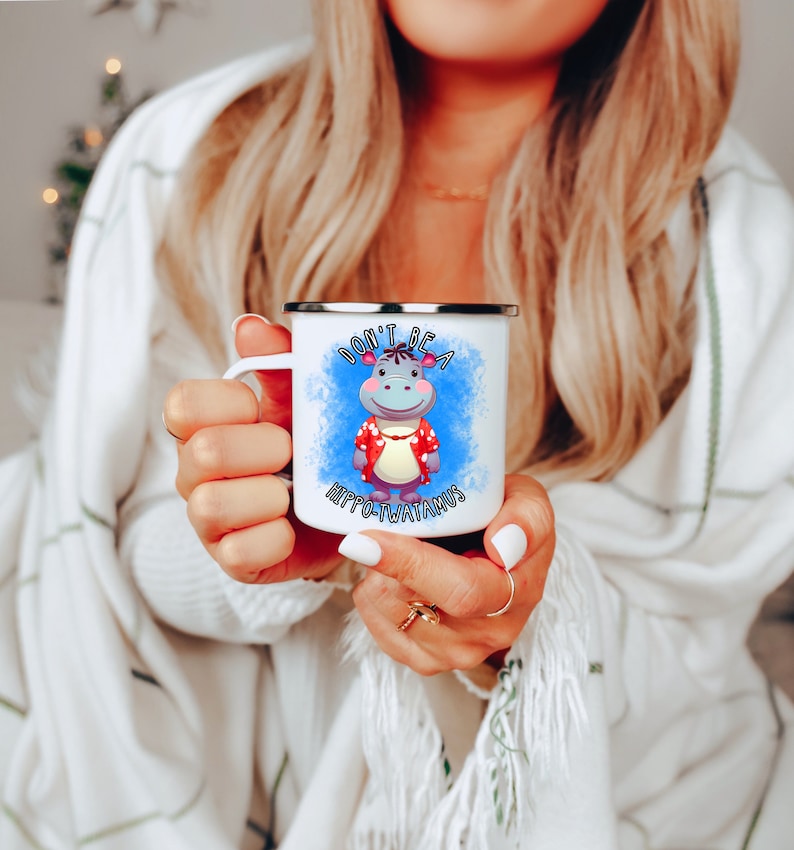 May include: White enamel mug with a blue and white watercolor background. The mug features a cartoon hippopotamus wearing a red and white Hawaiian shirt. The text "Don't be a Hippo-potamus" is printed on the mug.