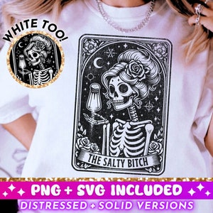 Puede incluir: Una camiseta blanca con una ilustración en blanco y negro de un esqueleto con una flor en el pelo. La ilustración está en el estilo de una carta de tarot y dice "The Salty Bitch". El texto "White Too!" está escrito en una fuente de brillo dorado en la camiseta.