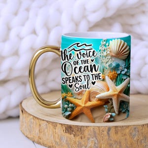 May include: White ceramic mug with a gold handle. The mug features a blue and green ocean scene with seashells, starfish, and the text "the voice of the ocean speaks to the soul".