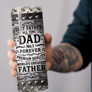 May include: A stainless steel tumbler with the words "BEST FATHER ALL TIME DAD No.1 FOREVER PREMIUM QUALITY WORLD'S GREATEST FATHER" printed in black and white. The tumbler has a diamond plate design and silver rivets.