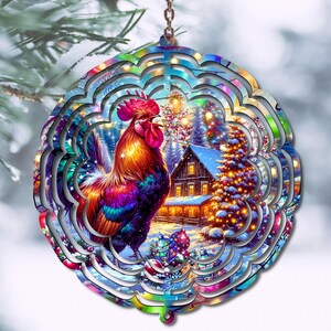 Puede incluir: Adorno navideño colorido con un gallo y una escena de paisaje invernal. El adorno tiene un diseño en capas con un gallo vibrante, árboles cubiertos de nieve y una cabaña acogedora. El adorno cuelga de una cadena.