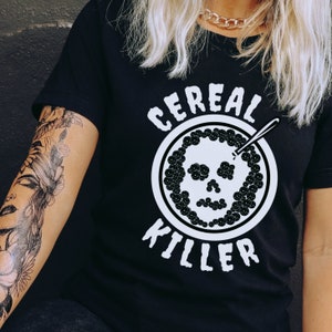 May include: Black t-shirt with a white graphic of a skull in a bowl of cereal with the text "Cereal Killer".