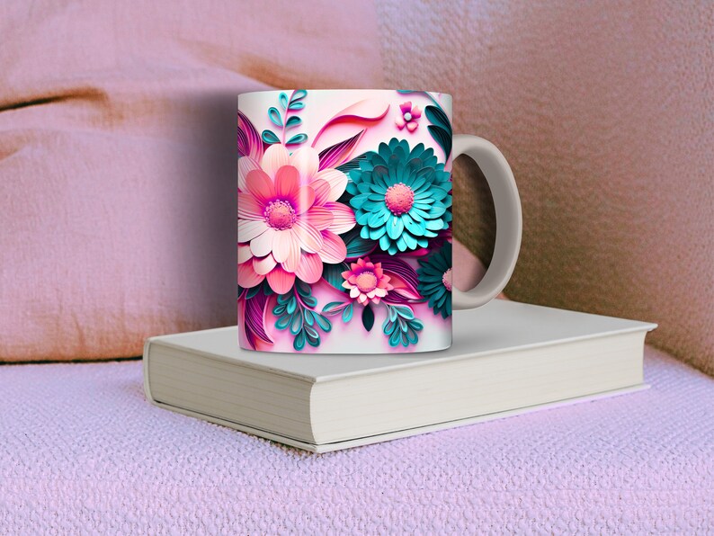 K&ouml;nnte beinhalten: Eine wei&szlig;e Keramiktasse mit einem farbenfrohen Blumendesign. Die Blumen sind rosa, blau und gr&uuml;n und haben eine papierartige Textur. Die Tasse hat einen wei&szlig;en Henkel.