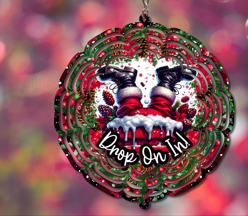 May include: A black metal wind spinner with a red and green Christmas design. Santa Claus is upside down with the text "Drop On In!" in a white circle.