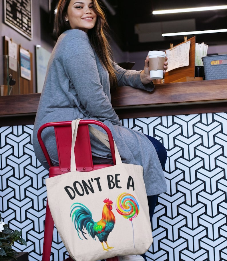 May include: A white canvas tote bag with the text "Don't be a" and a colorful rooster illustration holding a lollipop.