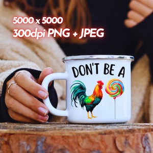 May include: White enamel mug with a black handle and the text "Don't be a" printed in black. A colorful rooster with a red comb and a colorful lollipop are printed on the mug.