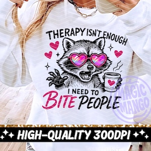 May include: White sweatshirt featuring a raccoon graphic wearing heart-shaped sunglasses and holding a coffee cup. The text says "Therapy isn't enough, I need to bite people." Pink hearts and stars are also included.