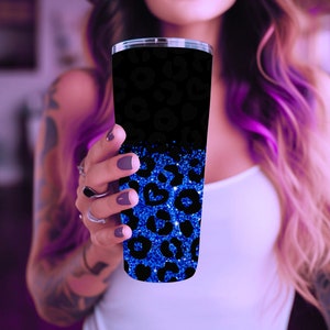 Op de afbeelding: Een zwarte en blauwe beker met een luipaardprint. De onderste helft van de beker is blauw glitter met een zwarte luipaardprint. De bovenste helft van de beker is zwart met een blauwe luipaardprint.