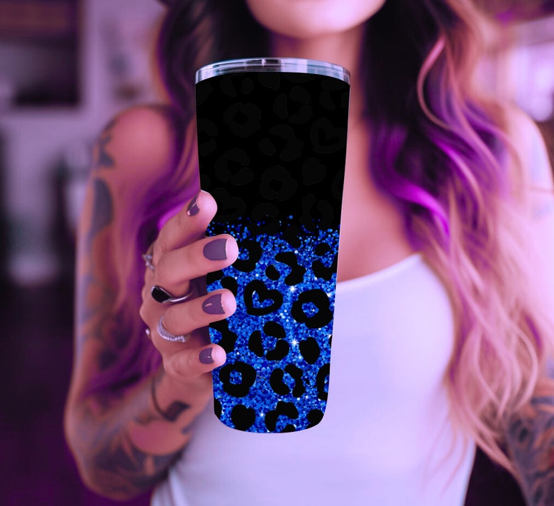 Op de afbeelding: Een zwarte en blauwe beker met een luipaardprint. De onderste helft van de beker is blauw glitter met een zwarte luipaardprint. De bovenste helft van de beker is zwart met een blauwe luipaardprint.