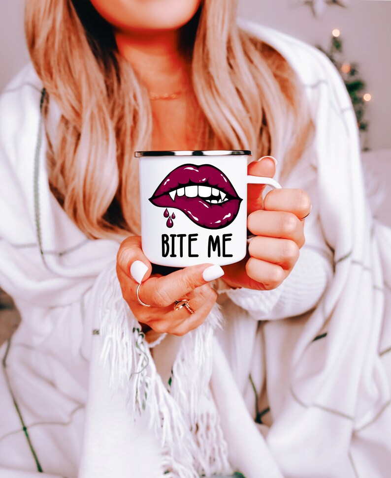 May include: White enamel mug with a red lip and fangs graphic and the text "Bite Me".