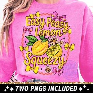 Może przedstawiać: Różowa bluza z kolorowym wzorem graficznym przedstawiającym cytryny, kwiaty i kokardy. Tekst brzmi "Easy Peasy Lemon Squeezy" w zabawnej czcionce. Projekt zawiera tekst "TWO PNGS INCLUDED".