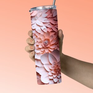 Pu&ograve; includere: Un bicchiere termico in acciaio inossidabile con un design floreale rosa e bianco. Il bicchiere ha un coperchio e una cannuccia.