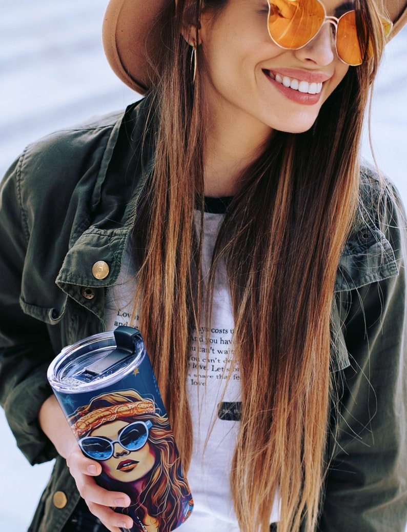 May include: A stainless steel tumbler with a black lid and a colorful graphic of a woman with sunglasses and a headband. The tumbler has a quote on it that reads "Love costs us nothing, but it gives us everything. Let's share this feeling of love."