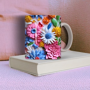 May include: A white ceramic mug with a colorful floral design. The flowers are pink, blue, yellow, and white. The mug has a handle on the right side.