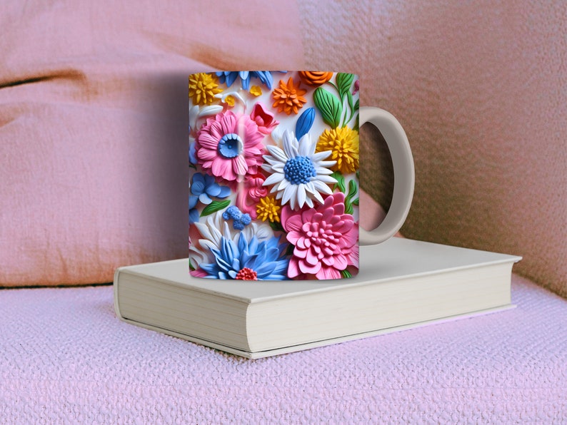 May include: A white ceramic mug with a colorful floral design. The flowers are pink, blue, yellow, and white. The mug has a handle on the right side.