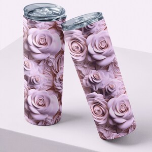 May include: Two stainless steel insulated tumblers with a floral rose pattern in shades of pink. The tumblers have clear lids and are displayed on a white surface. The rose design covers the entire surface of the tumblers.