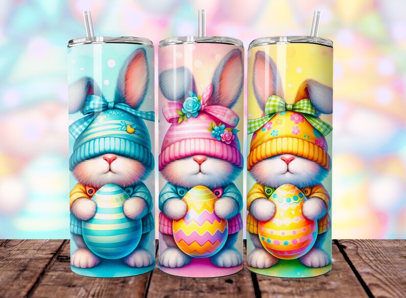 May include: Three Easter-themed stainless steel tumblers with colorful bunny designs. Each bunny is wearing a hat and holding an Easter egg. The tumblers are perfect for spring celebrations.