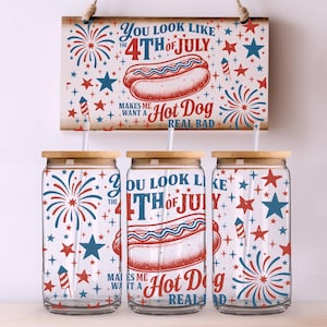 May include: Three glass tumblers with wooden lids and straws, decorated with red, white, and blue fireworks, stars, and the text "You look like the 4th of July, makes me want a hot dog real bad." A wooden sign with the same design hangs above.