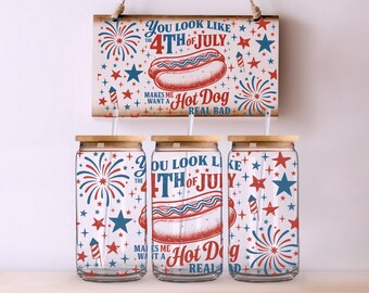 Puede incluir: Tres vasos de vidrio con tapas y pajitas de madera, decorados con fuegos artificiales, estrellas rojas, blancas y azules, y el texto "You look like the 4th of July, makes me want a hot dog real bad." Un letrero de madera con el mismo diseño cuelga arriba.