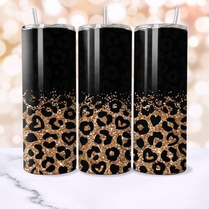 Op de afbeelding: Drie zwarte en gouden roestvrijstalen bekers met een luipaardprint en glitterontwerp. De bekers hebben een rietje en een deksel.