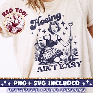 May include: A white t-shirt with a graphic of a woman gardening. The graphic says "Hoeing Ain't Easy" and features a woman with a basket and a shovel. The text "Red Too!" is in a circle above the graphic.