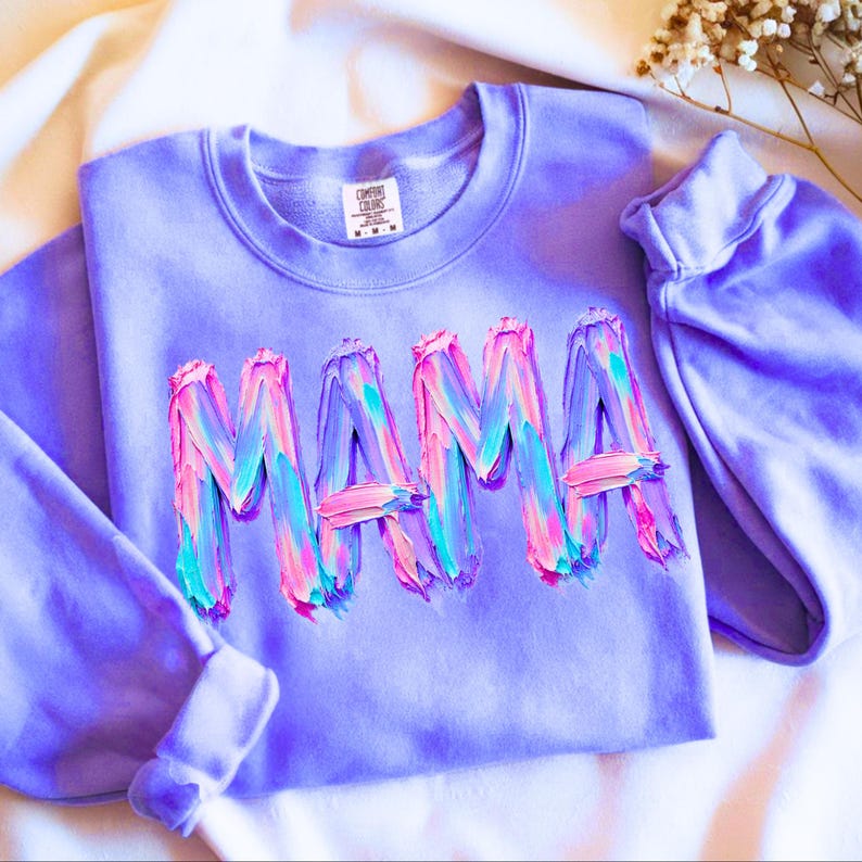 The word "MAMA" rendered in a thick, three-dimensional impasto oil paint style. The bold, capitalized letters are formed from heavy, visible brushstrokes in a vibrant swirling blend of bright pink, cyan blue, and deep lavender. The textured paint creates a high-relief, artistic effect with rich, tactile details. This expressive, painterly design features a modern and energetic aesthetic, appearing as if sculpted from thick, layered, wet oil paint.