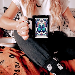 May include: Black coffee mug with a colorful butterfly illustration and the text "The Antisocial Butterfly".