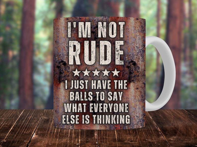 May include: A white ceramic mug with a rusty metal design. The mug has a black text that reads "I'M NOT RUDE I JUST HAVE THE BALLS TO SAY WHAT EVERYONE ELSE IS THINKING".