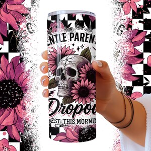 May include: A white tumbler with a black and white checkered background. The tumbler has a pink and black skull with flowers and the text "Gentle Parents Drop Out Est. This Morning".