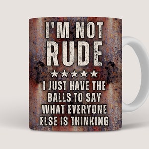 May include: A white ceramic coffee mug with a rusty brown background. The mug has a white handle and features the text "I'M NOT RUDE I JUST HAVE THE BALLS TO SAY WHAT EVERYONE ELSE IS THINKING".
