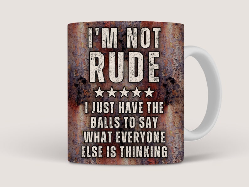 May include: A white ceramic coffee mug with a rusty brown background. The mug has a white handle and features the text "I'M NOT RUDE I JUST HAVE THE BALLS TO SAY WHAT EVERYONE ELSE IS THINKING".