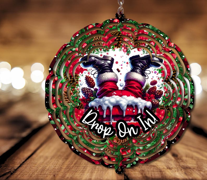 May include: A red and green Christmas wind spinner with a white background. Santa's legs are sticking out of a chimney with the text "Drop On In!"