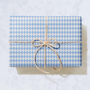 Puede incluir: Un regalo envuelto en papel de regalo con un patrón de diamantes azules y blancos, atado con hilo. Las palabras "Clásico", "Atemporal" y "Estético" están en la parte superior. Las palabras "Papel de regalo elegante" están en la parte inferior.