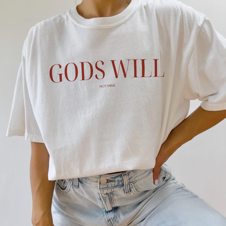 May include: White t-shirt with the text "GODS WILL NOT MINE" printed in red.