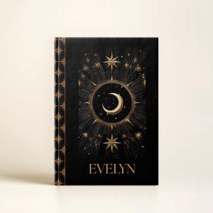May include: Black journal with gold celestial design featuring a crescent moon, stars, and the name "EVELYN". The spine has a repeating star pattern. The cover design is centered with a detailed, artistic style.