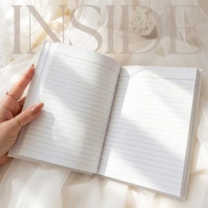 May include: An open notebook with white pages featuring horizontal black lines for writing. The word INSIDE is printed in large, light-colored capital letters across the top of the open pages, which are illuminated by soft, natural light.
