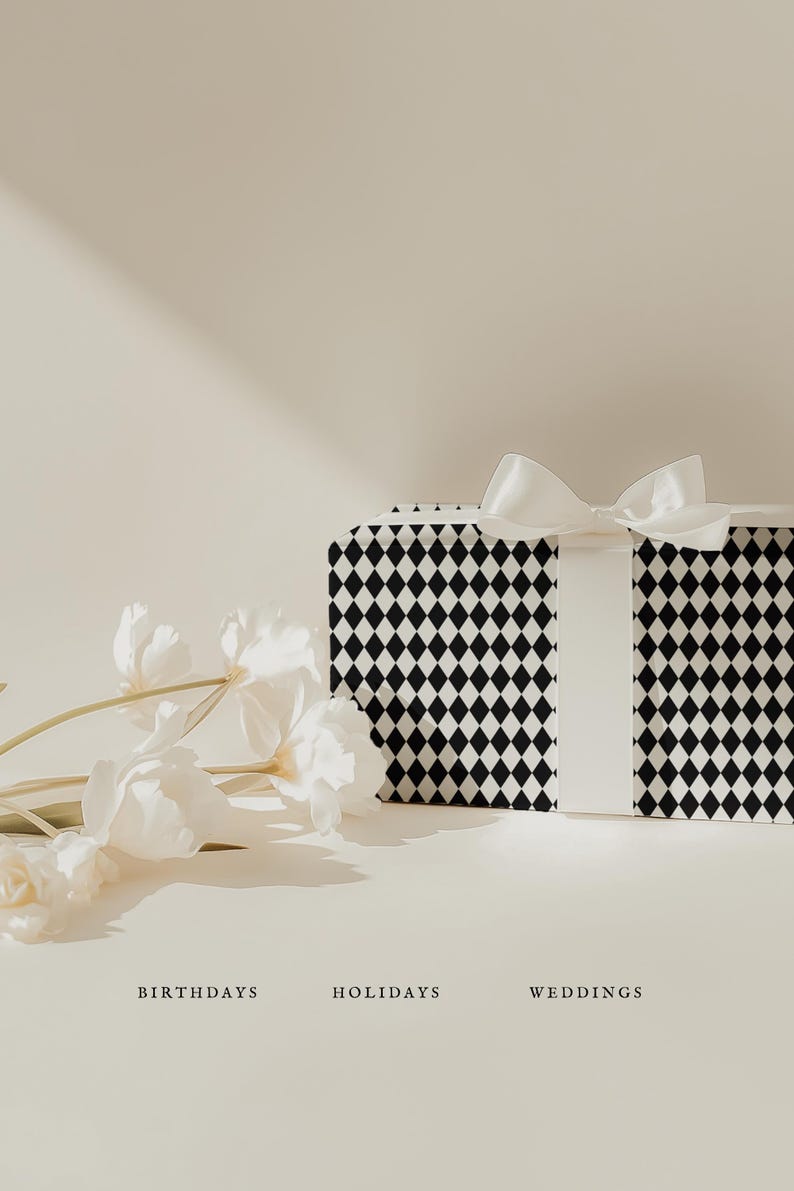 May include: A rectangular gift box wrapped in black and white diamond patterned paper, tied with a white satin ribbon. White flowers are arranged to the left. The words "BIRTHDAYS", "HOLIDAYS", and "WEDDINGS" are below.