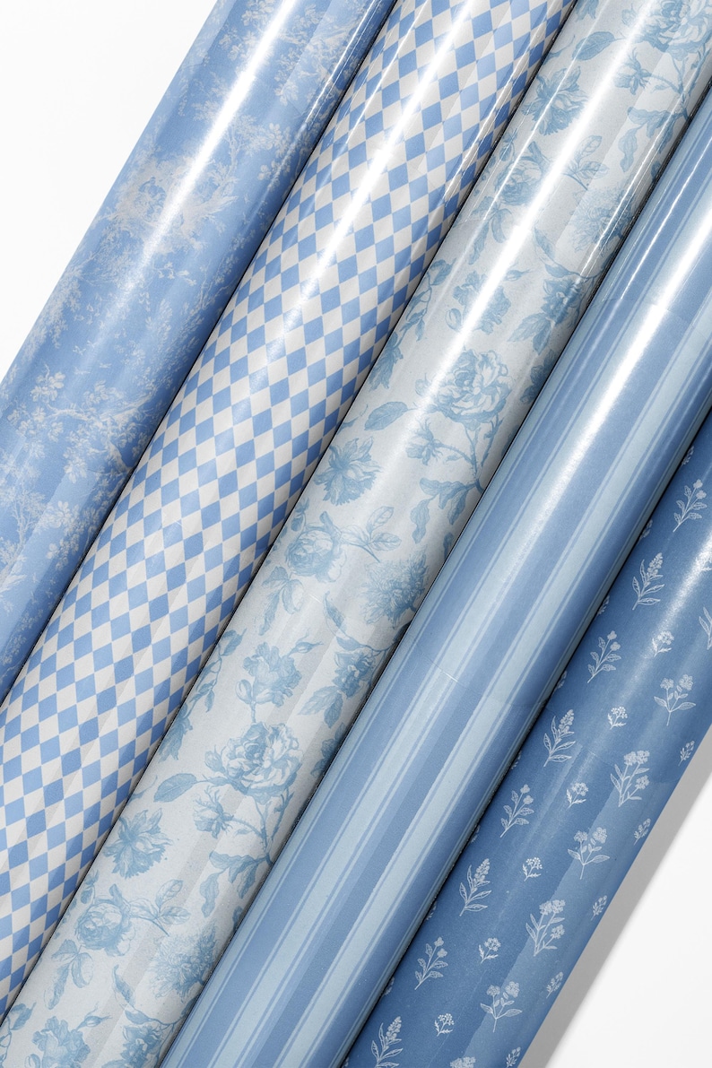 May include: A collection of rolled wrapping paper in various patterns. Designs include floral, diamond, and striped patterns in shades of blue and white. The paper has a glossy finish.