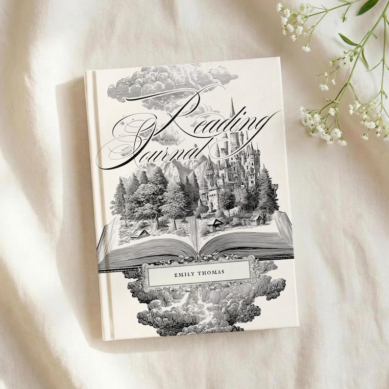 Peut inclure: Un livre de journal de lecture &agrave; couverture rigide avec une illustration d&eacute;taill&eacute;e en noir et blanc d'un ch&acirc;teau, de montagnes et d'arbres. La couverture du livre porte le nom "Emily Thomas" et une &eacute;criture d&eacute;corative. Le livre est sur une surface blanche.