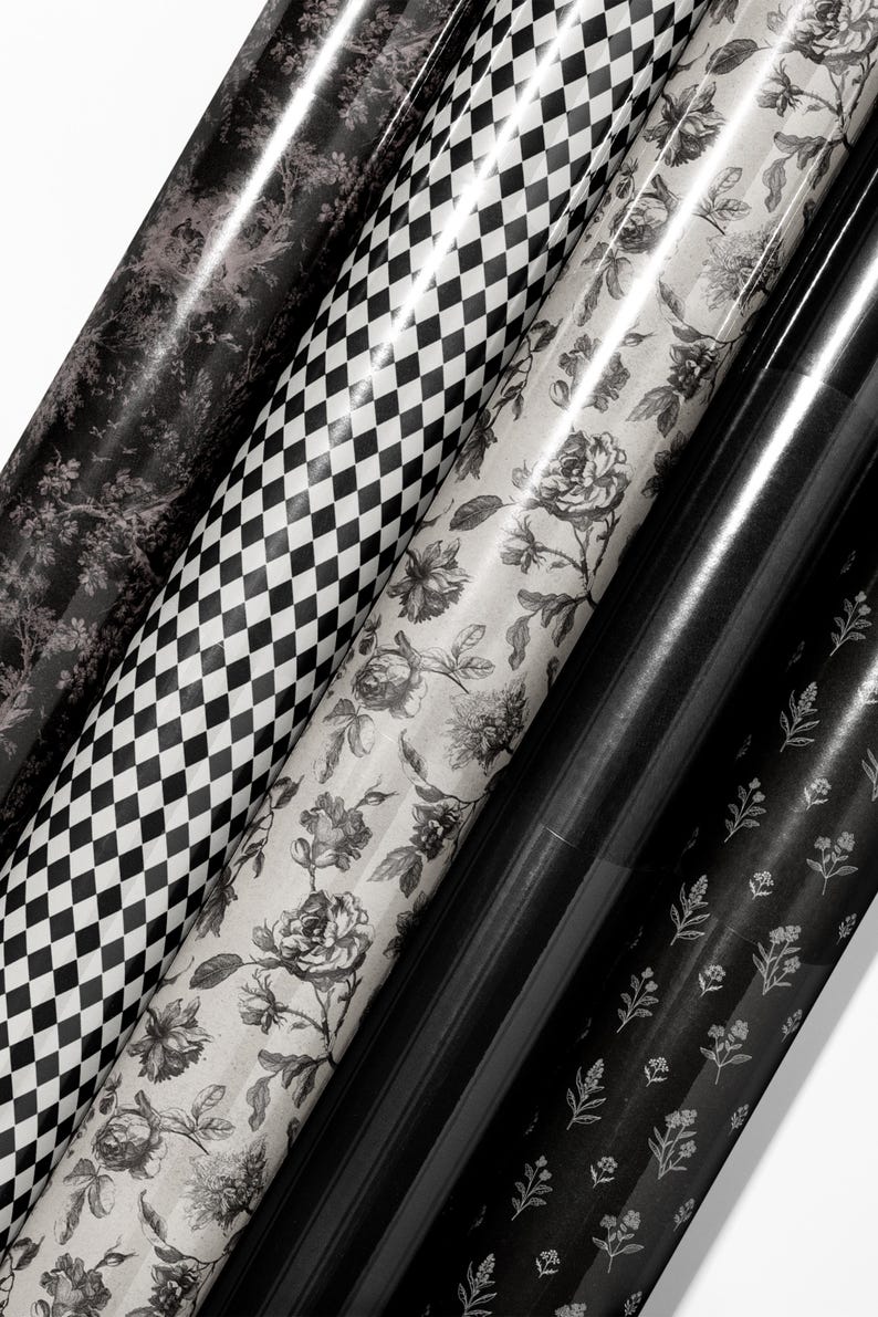 May include: Assortment of rolled wrapping paper with various patterns. Designs include a black and white checkerboard, floral, and botanical prints. The paper is in shades of black, white, and gray, creating a monochromatic aesthetic. Ideal for gifts and crafts.