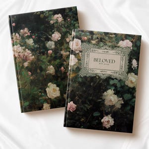 K&ouml;nnte beinhalten: Zwei Hardcover-Journale mit einem floralen Design mit rosa Rosen und gr&uuml;nen Bl&auml;ttern. Der Einband eines Journals tr&auml;gt den Text "BELOVED EST 2023" in einem dekorativen Rahmen.