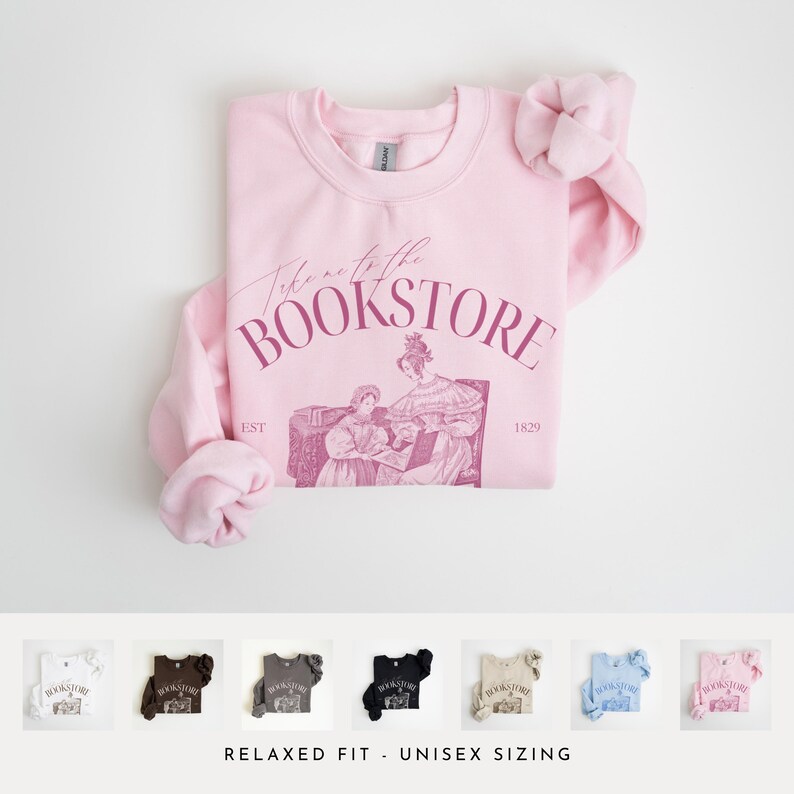 May include: Pink sweatshirt with the text "Take me to the Bookstore" in a pink script font. The sweatshirt features a vintage illustration of two women reading a book. The text "EST 1829" is printed below the illustration.