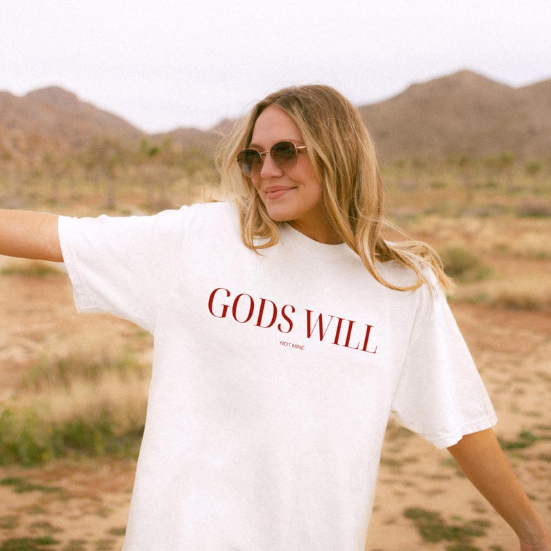 May include: White t-shirt with the text "GODS WILL NOT MINE" printed in red.