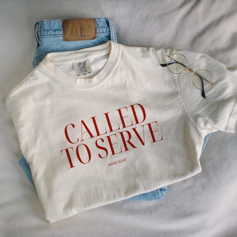 May include: A white t-shirt with the words "Called to Serve" in red lettering and the scripture reference "Mark 10:45" underneath.
