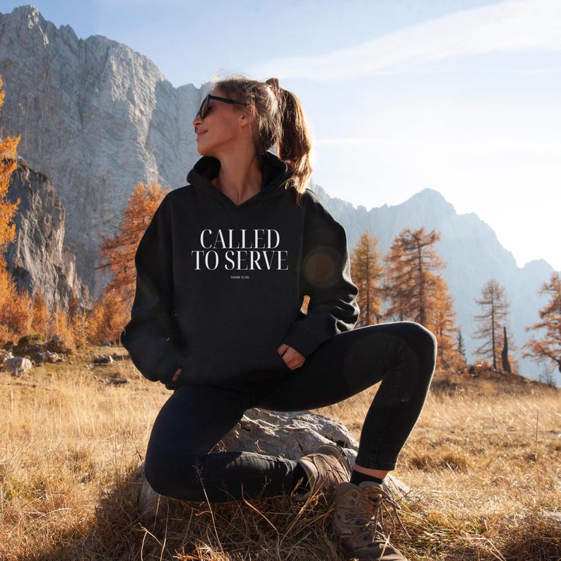 May include: A black hoodie with the text "CALLED TO SERVE" in white lettering. The hoodie is worn by a person standing in a mountainous landscape.