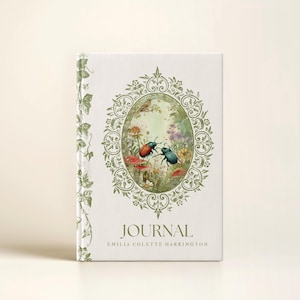 May include: A hardcover journal with a cream-colored cover. The cover features a green oval frame with a nature scene of beetles, mushrooms, and flowers. The word "JOURNAL" is printed below the frame, with the author's name beneath.