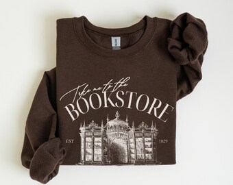 May include: A brown sweatshirt with the text "Take me to the Bookstore" in white lettering. The text is above a drawing of a bookstore with the text "EST 1829" below the drawing.