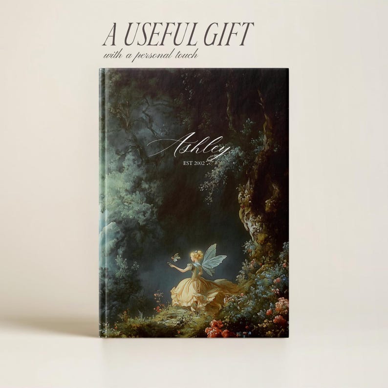 Puede incluir: Un diario personalizado con una escena de bosque verde oscuro y azul que presenta una hada con alas y un vestido amarillo. El texto "Ashley EST 2002" est&aacute; impreso en la portada.