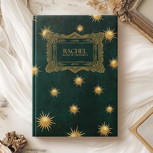 Puede incluir: Un diario verde oscuro con un marco dorado adornado y el texto "Rachel Notes & Thoughts". La portada está decorada con un patrón repetido de estrellas doradas.